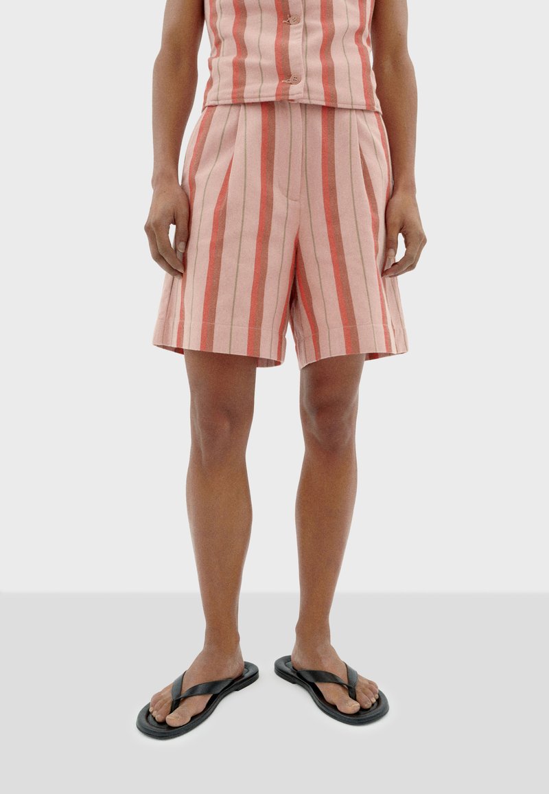 Roze gestreepte shorts met een losse pasvorm, voorzien van plooien en zijzakken. Gedragen met zwarte flip-flops voor een casual uitstraling.