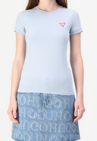 T-shirt aderente azzurro chiaro con maniche corte e scollatura rotonda, con un logo triangolare rosso sul lato sinistro del petto.