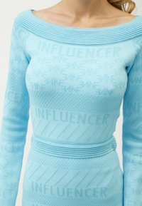 Abito azzurro fitted con scollatura off-shoulder, tessuto texture e motivo ripetuto "INFLUENCER". Dettagli a coste sulle spalle e in vita.