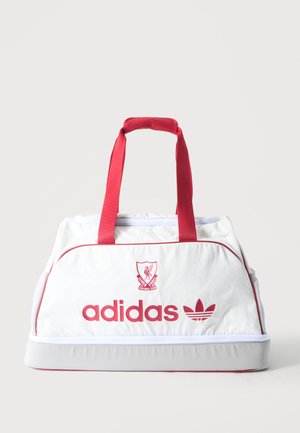 Λευκή αθλητική τσάντα Adidas με κόκκινες λαβές, το έμβλημα του Liverpool Football Club και κόκκινο λογότυπο Adidas μπροστά.