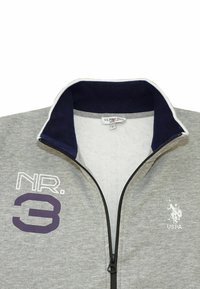 Felpa grigia con zip e colletto blu navy, caratterizzata da un logo bianco e testo viola "NR. 3". Realizzata in tessuto morbido, ideale per un abbigliamento casual.