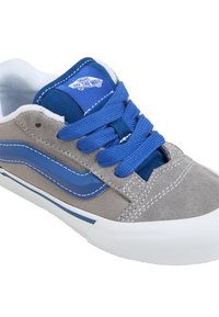 Graue und blaue Sneakers aus Wildleder und Canvas-Material, runde Zehenpartie, weiße Gummisohle, blaue Schnürsenkel und ein Logo auf der Zunge.