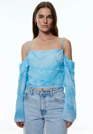 Lichtblauwe crop top met off-the-shoulder mouwen, met een gelaagd ontwerp en een marmerpatroon. Gecombineerd met hoge taille denim jeans.