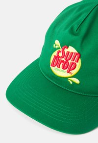 Căciulă de baseball din bumbac verde cu o coroană rotundă. Prezintă logo-ul brodat "Sun Drop" în culorile galben și roșu, cu accente în formă de stropi pe față.