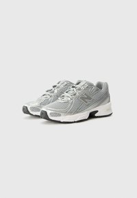 Zapatillas de correr ligeras en plateado, con parte superior de malla, collar acolchado y suela de goma negra. Incluyen cordones y detalle del logo en el lateral.