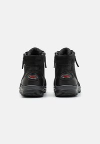 Baskets montantes noires avec un extérieur en cuir lisse, des accents texturés, une fermeture éclair sur le côté et une semelle en caoutchouc confortable.