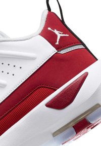 Sneaker rosso e bianco con tomaia testurizzata, accenti in pelle liscia e un'unità d'aria visibile nella suola. Logo ricamato sul lato.