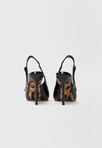 Scarpe con tacco alto in vernice nera con design alla slingback. Insonorizzazione notevole con stampa leopardata e finitura lucida e raffinata.