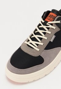 Sneakers avec un mélange de textile noir et de daim gris, des lacets blancs, un col rembourré et une semelle en caoutchouc ivoire texturée.