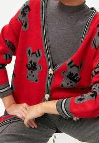 Cardigan rosso con motivi di orsi grigi, design a V, con chiusura a bottoni, accenti a righe grigie sui polsini e una morbida texture lavorata a maglia.