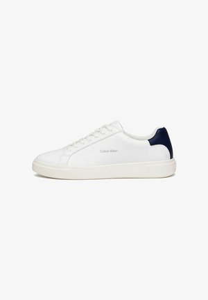 Zapatilla blanca de corte bajo con cordones en la parte delantera, lengüeta azul marino en el talón y el logo "Calvin Klein" en el lateral, vista desde el exterior.
