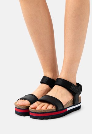 Sandali platform neri con cinturini regolabili, soletta in sughero, suola in gomma testurizzata e accenti sovrapposti rossi e blu sulla base.