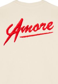 Felpa crema con testo ricamato rosso "Amore", caratterizzato da uno stile corsivo prominente e una texture liscia. Design semplice e minimalista.