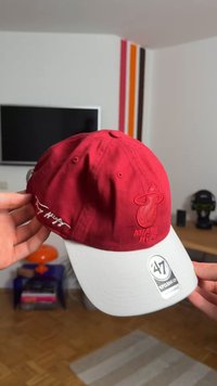 Rdeča bejzbol kapa z belo šiltom, z logotipom Miami Heat spredaj in izvezenim podpisom na strani. Narejena iz blaga.