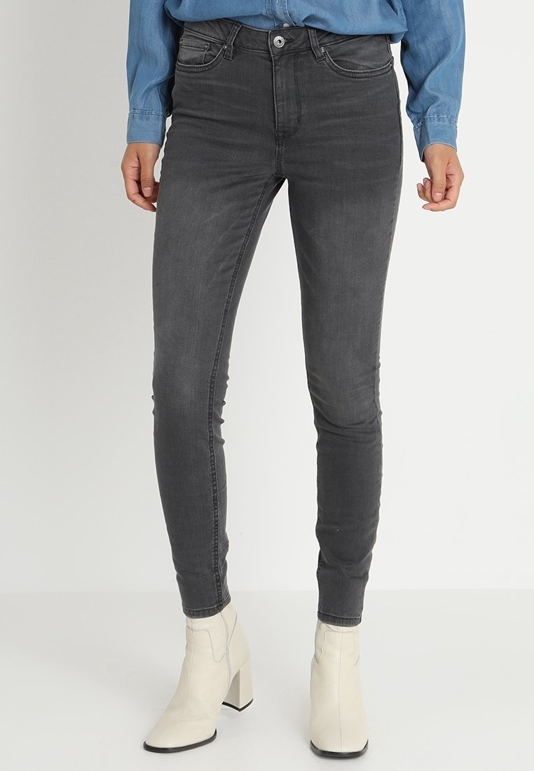 Jeans gris ajustados hechos de denim, con cinco bolsillos, cierre de botón y un diseño minimalista. Combinados con botas blancas hasta el tobillo.
