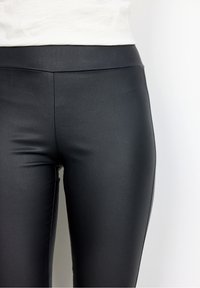 Höga svarta leggings gjorda av ett smidigt, stretchigt material med en slank, figurnära design och utan synliga mönster eller hårdvara.