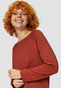 Gestreifter, rostfarbener Langarmoberteil mit weitem Kragen. Der Stoff weist horizontale Streifen und eine strukturierte Oberfläche auf.