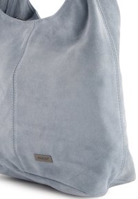 Wildleder-Schultertasche in Hellblau, mit feinen Steppnähten und einem kleinen Metallschild. Weiche Textur und abgerundete Form.