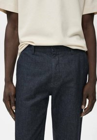 Donkerblauwe broek van denim, met een rechte snit, klassieke knoopsluiting en zakken aan de voorkant. Eenvoudig, strak ontwerp zonder patronen.