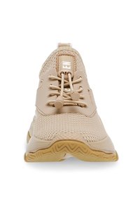 Beige idrottssko med ovandel i mesh och gummisula, med rund snörning, vadderad krage och en logotagg nära snörningsområdet.