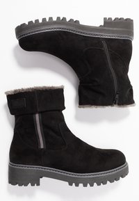 Bottines en suède noir avec un revers replié, doublure en fourrure grise, fermeture éclair latérale et semelle en caoutchouc robuste avec des crampons profonds pour une bonne adhérence.
