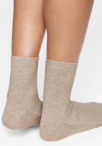Calzini alla caviglia a coste beige, realizzati in un materiale morbido e testurizzato, con talloni e punte rinforzati, caratterizzati da un design semplice dell'orlo.