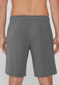 Pantalones cortos deportivos grises hechos de una tela suave, con una cinturilla elástica y un corte relajado, que terminan justo por encima de las rodillas.