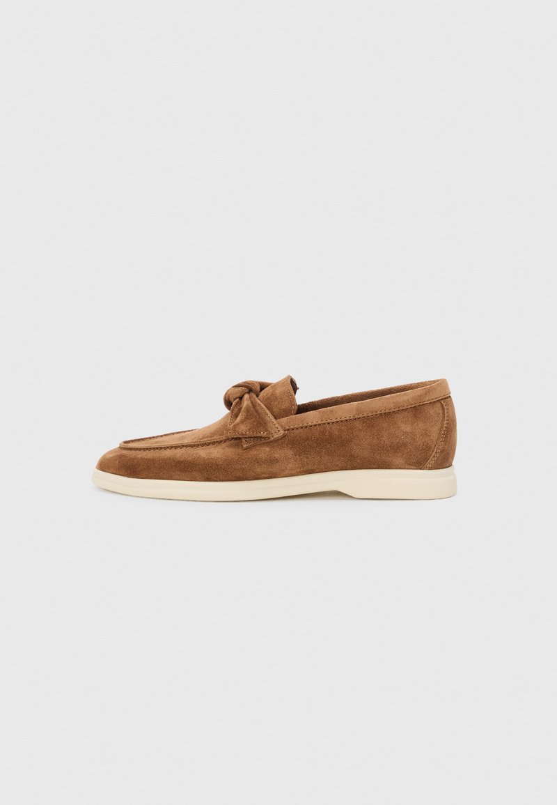 Mocassins en daim marron avec un accent de nœud noué, un design bas et une semelle en caoutchouc crème contrastante.
