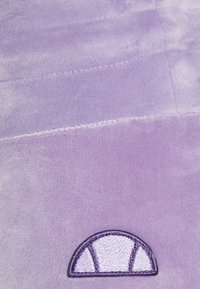 Tissu violet doux avec des coutures horizontales piquées et un petit motif de demi-cercle brodé près du bord inférieur.