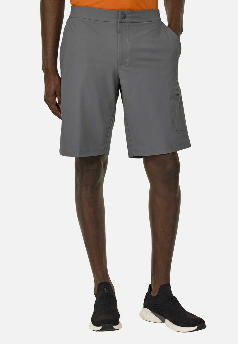 Pantaloni cargo grigi con taglio dritto, tasche laterali e chiusura a bottone. Indossati con scarpe da ginnastica nere e una maglietta arancione.