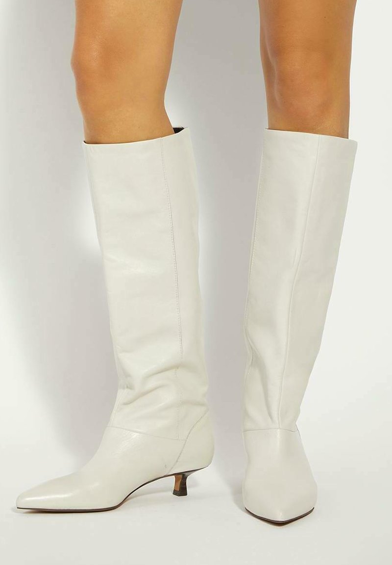 White knee-high boots made of leather, featuring a pointed toe and a small heel. Smooth texture with minimal stitching details.