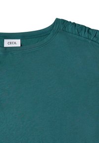 Chemise vert sarcelle avec encolure ronde et détail de tissu froncé à l'épaule, étiquetée avec la marque "CECIL".