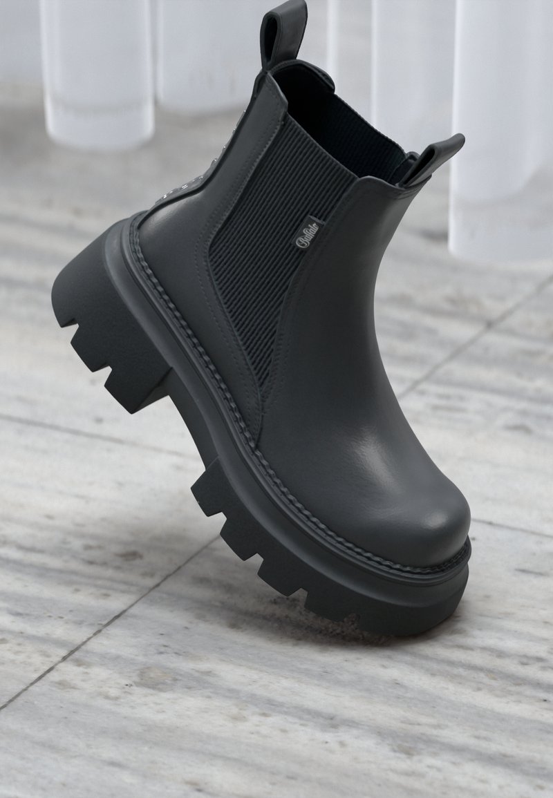 Čierne členkové topánky vyrobené z hladkej kože, obsahujúce elastické bočné panely, robustnú podrážku s dezénom a pútka pre jednoduché obúvanie.