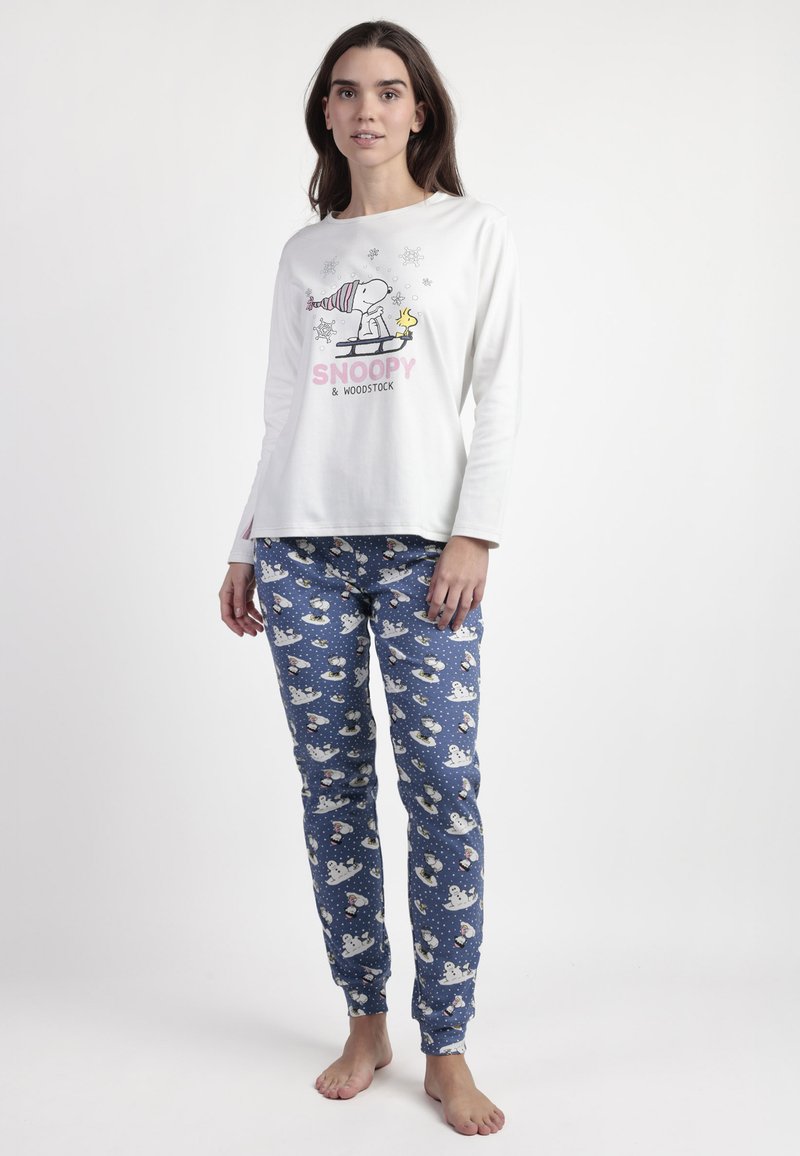 Camisa de pijama blanca de manga larga con un gráfico de Snoopy y Woodstock, combinada con pantalones de pijama azules con patrones de muñecos de nieve y puntos.