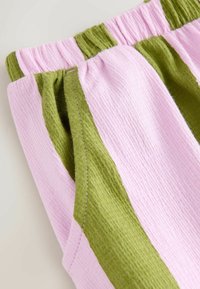 Cottonbukser med iøjnefaldende pink og grønne vertikale striber, blød elastisk talje og sidelommer for ekstra funktionalitet.