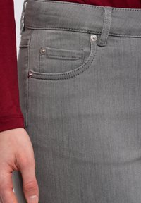 Gray denim skirt with front pocket detail, silver hardware button, and contrasting stitching. Smooth texture and fitted design.