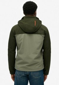 Olijfgroen jack met een grijze inzet, capuchon en "Superdry" logo. Het jack heeft een gladde stof en een sportief ontwerp, geschikt voor casual kleding.