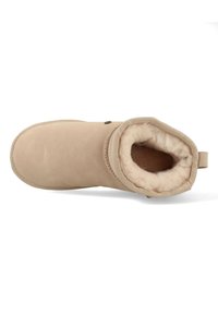 Beige enkelboot van suede met een zachte, faux fur voering en een ronde neus. Heeft een gestikt naad en een trekriem bij de hak.