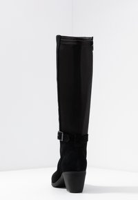 Stivali neri al ginocchio realizzati con una combinazione di materiali lisci e scamosciati, design con tacco, zip laterale e un accento decorativo a forma di fibbia.