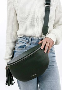 Tamsiai žalia oda, crossbody maišelis su tekstūruotu paviršiumi, užtrauktuko uždarymu ir kutu. Reguliuojama juosta su metalinėmis detalėmis.