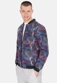 Heren bomberjack in een multikleurig golfpatroon met tinten paars, blauw en roze; marineblauwe geribde kraag en manchetten.