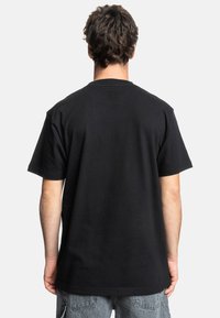 Černé krátké rukávy bavlněné tričko s kulatým výstřihem, hladká textura a minimální švy na zadní straně.