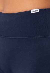 Marinblå högmidjade leggings i ett mjukt och elastiskt material. Utrustade med en mjuk midjeresår med en liten vit "SMILODOX"-tag.