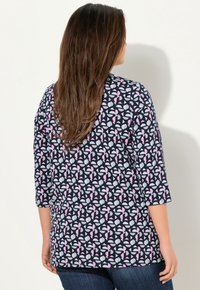 Granatowa bluzka z ¾ rękawami, z geometrycznym wzorem w różowym i jasnoszarym kolorze. Miękka tkanina z lekko teksturowanym wykończeniem.