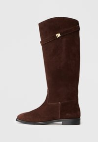 Stivale marrone in suede fino al ginocchio con punta tondeggiante e suola nera piatta; presenta una fascia decorativa dorata con le iniziali.