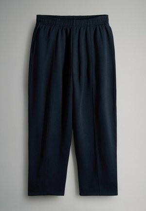 Tumedat meresinised sportlikud püksid, mis on valmistatud pehmest kangast, elastse vöökohtaga ja kitsenevate jalgadega, mille külgsuunalised õmblused annavad neile vormi.