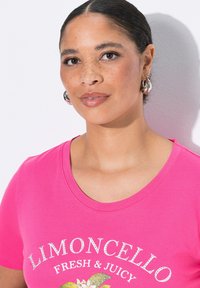 T-shirt rose vif avec un col rond, comportant le texte « LIMONCELLO FRESH & JUICY » et un motif floral, rehaussé de ruissellements.