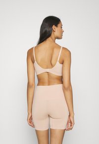 Light beige bra and shorts set, seamless design, soft stretch fabric, adjustable straps, and wide waistband with smooth finish.