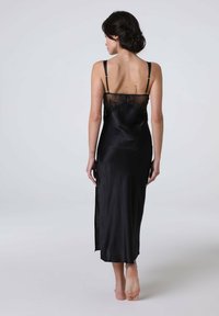 Abito in satin nero con pannello posteriore in pizzo, spalline sottili e apertura laterale. Texture liscia e design di lunghezza media.