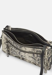 Slangenprint leren tas met een ritsluiting, voorzien van een zwarte binnenkant, meerdere vakken en accenten van zilver hardware.